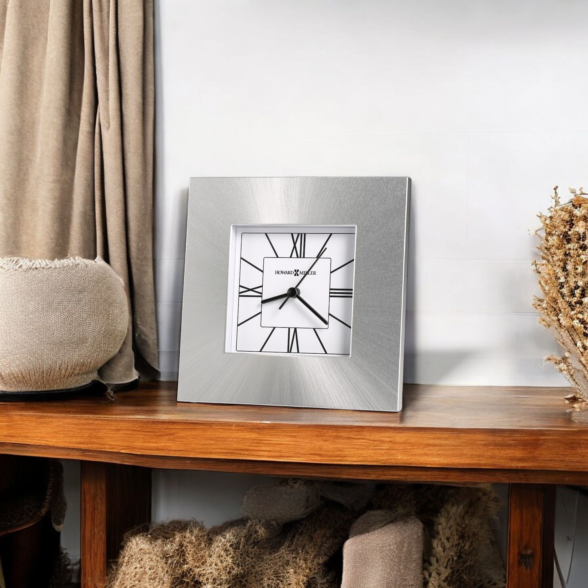 A decorative silver-framed wall clock on a wooden shelf.