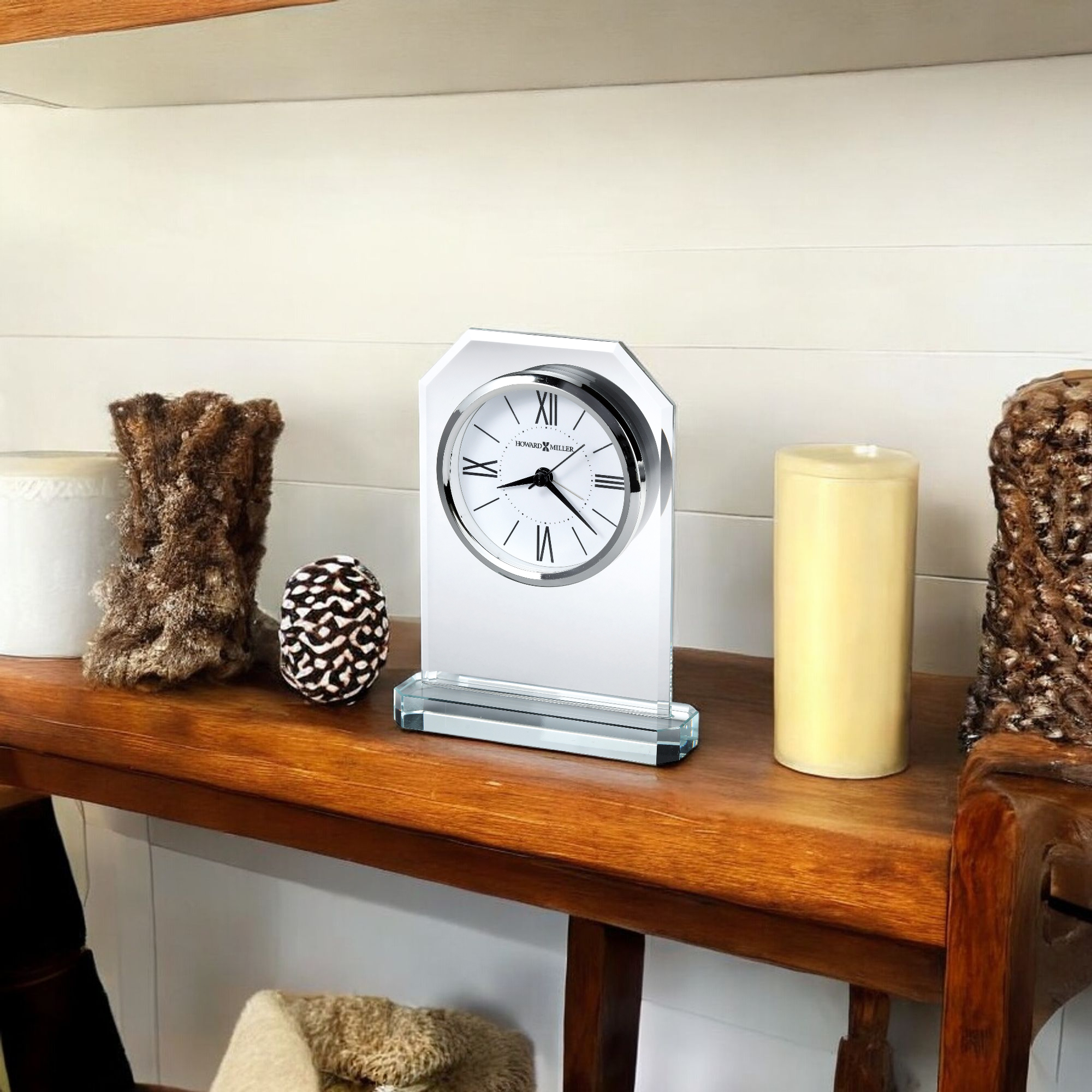 A decorative clock displayed on a wooden shelf, surrounded by various decorative items.