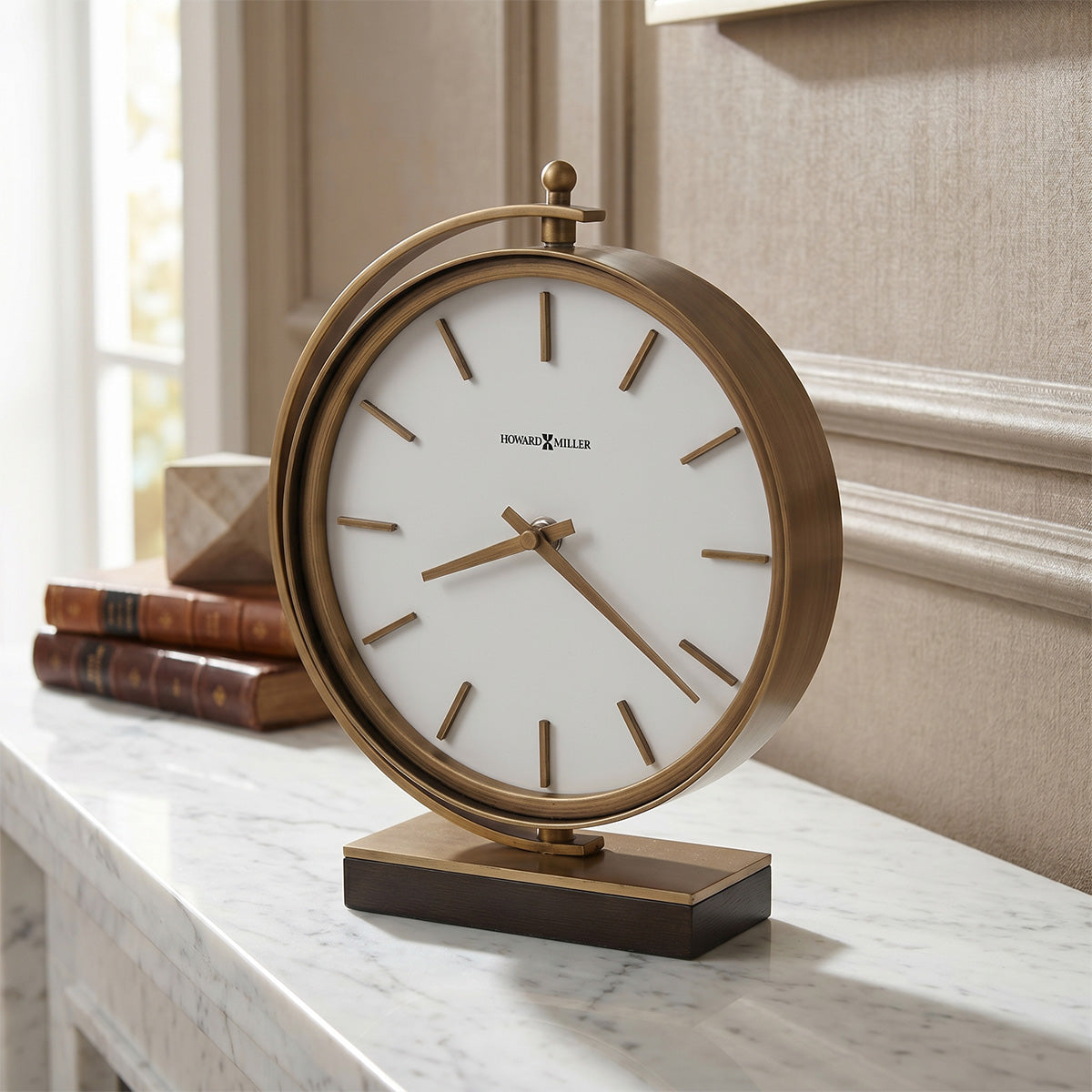 A stylish vintage accent clock with a round bronze frame and a white face, featuring simple hour markers and hands on a marble mantel piece.