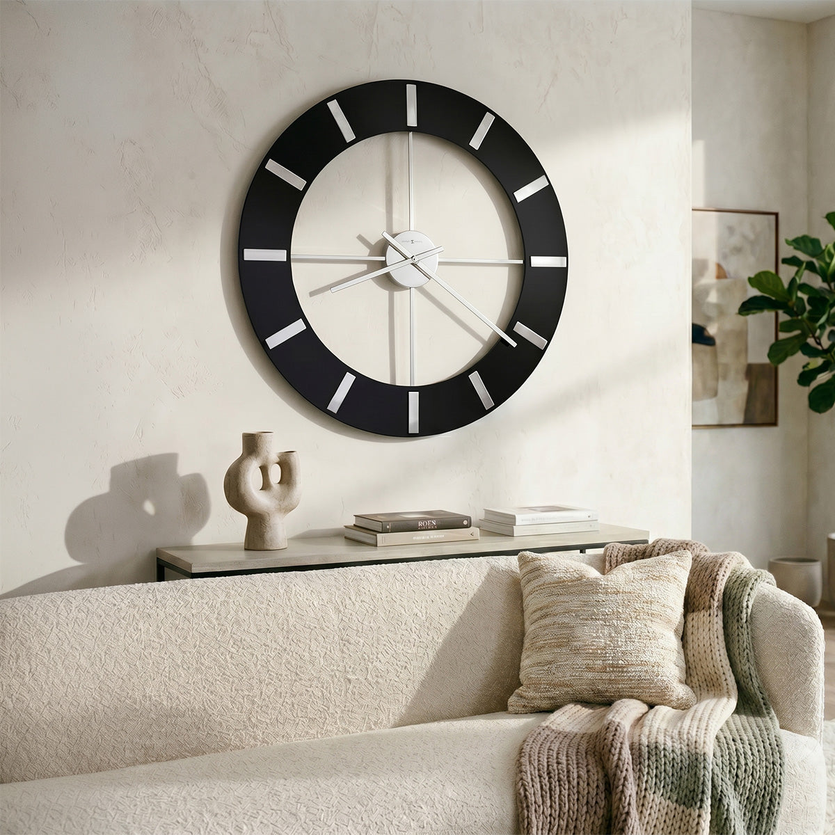 Large wall clock with black frame and white face in a living room setting.