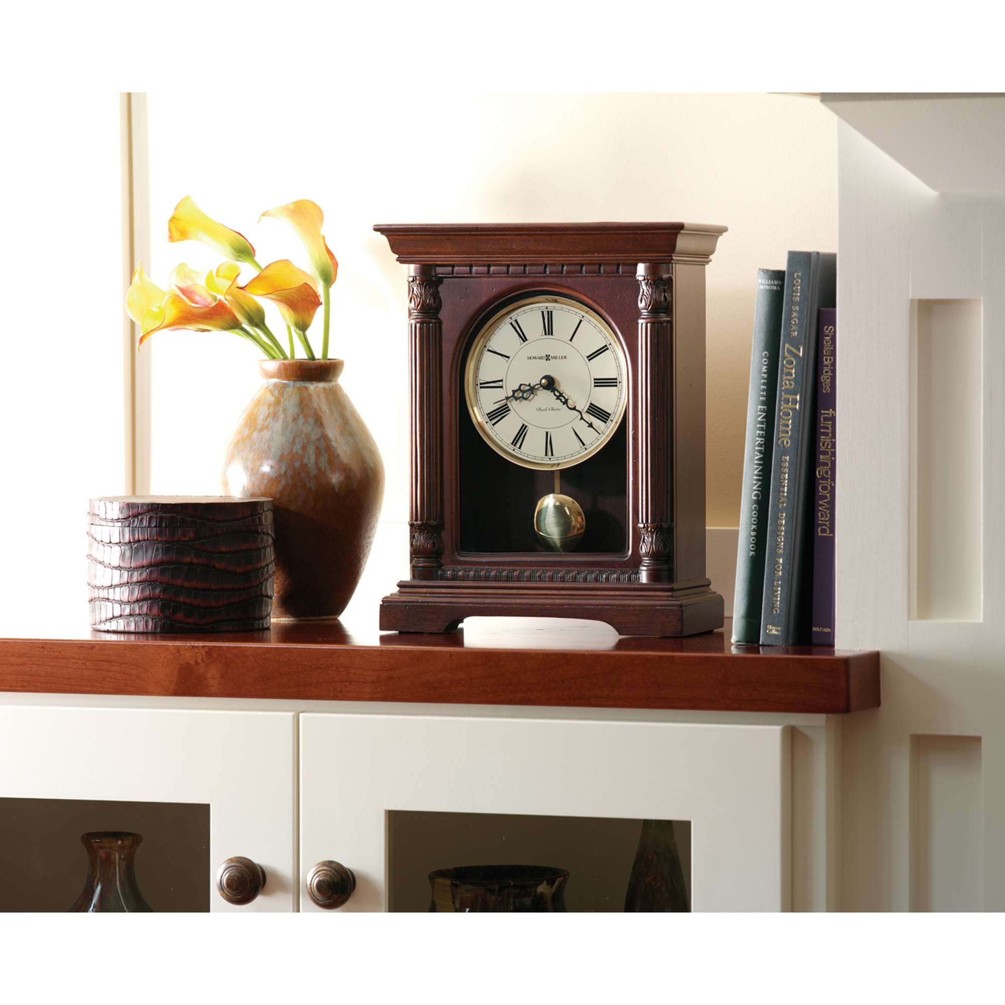 Antique wooden clock displayed on a shelf with decorative items and books.