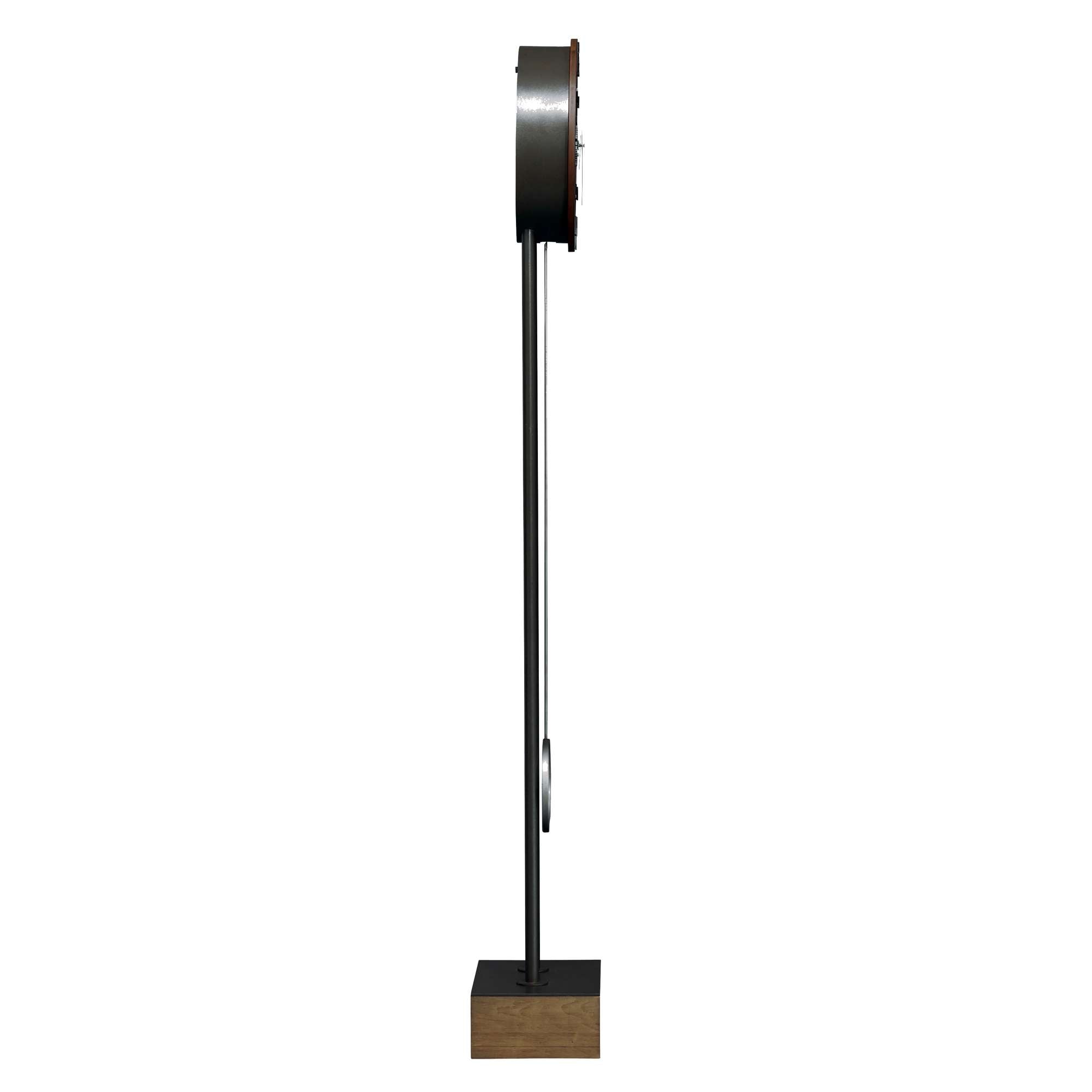 A modern wall clock with a minimalist design mounted on a sleek metal stand.