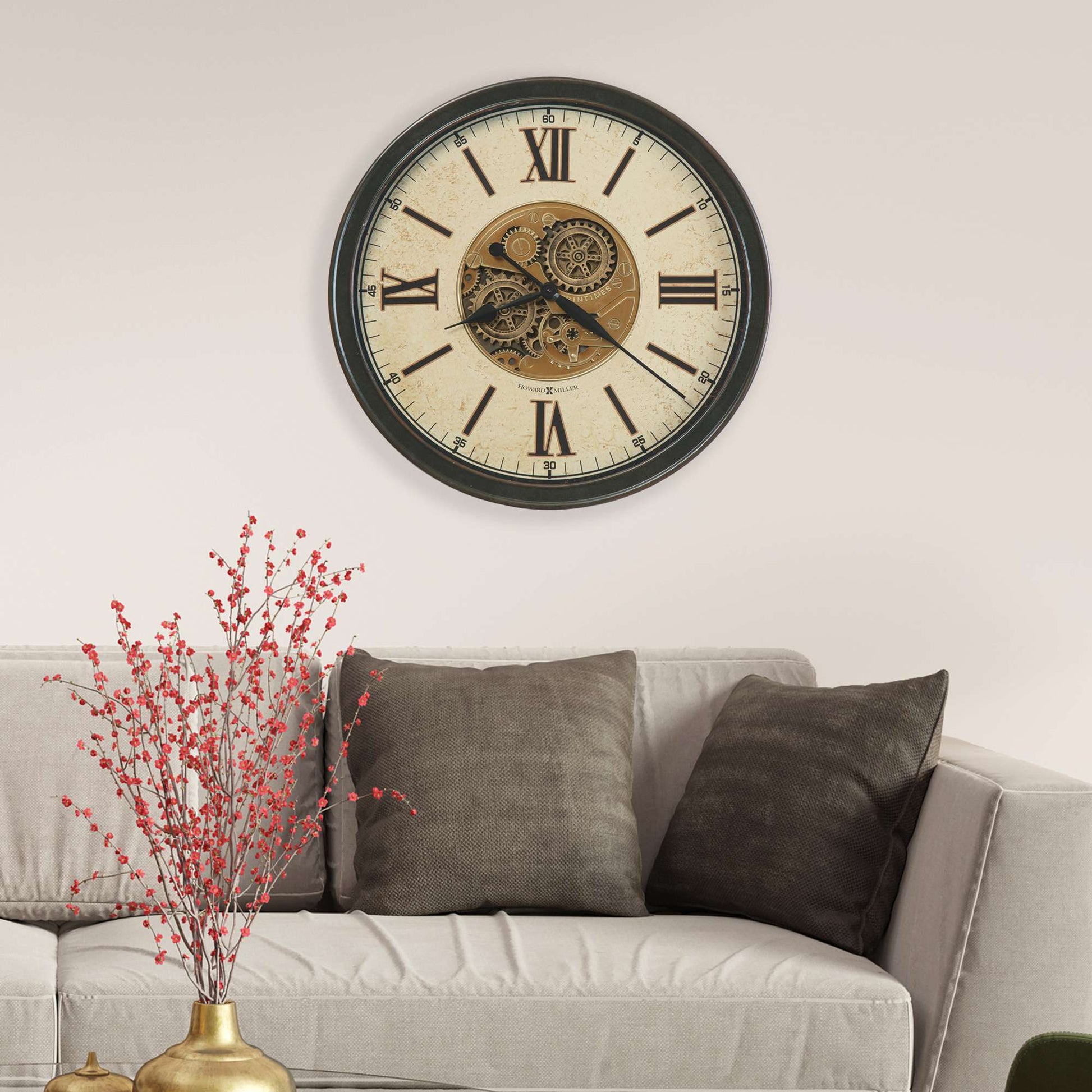 Old-fashioned wall clock above a modern gray sofa with decorative pillows.