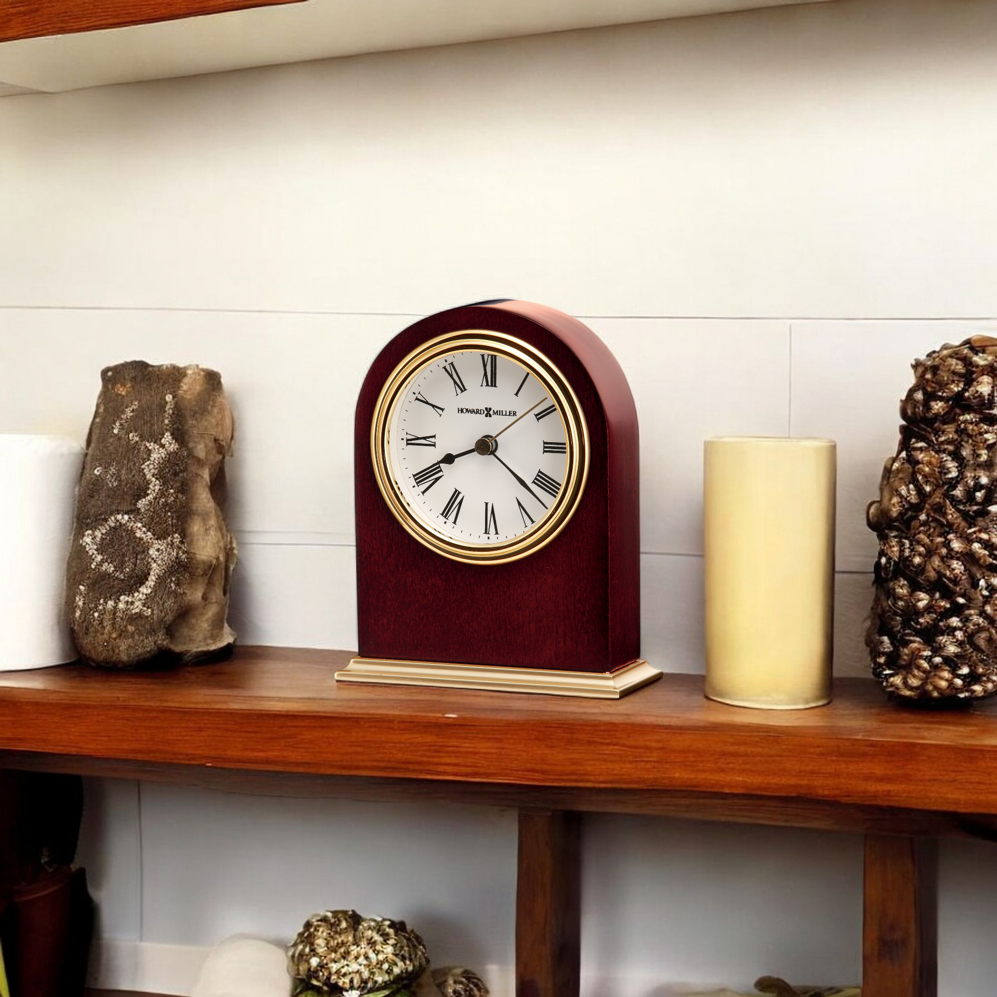 Classic clock on a wooden shelf surrounded by decorative objects