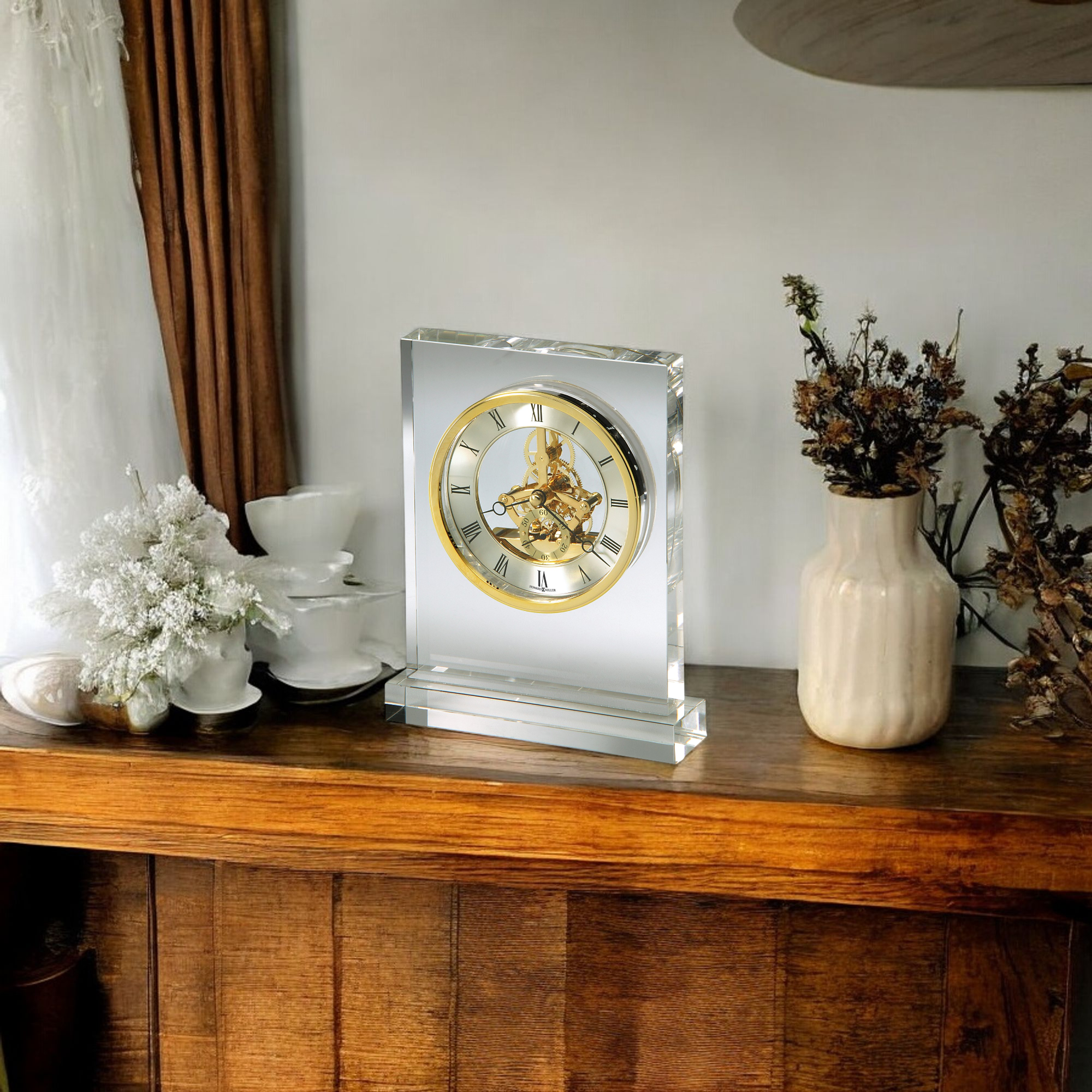 A decorative clock on a wooden shelf with white flowers and a ceramic vase.
