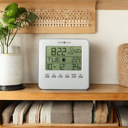 Digital weather station displaying time, date, temperature, and humidity on a wooden shelf.