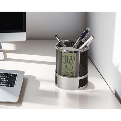 A modern desk organizer holding pens and a digital clock, placed next to a laptop on a clean workspace.