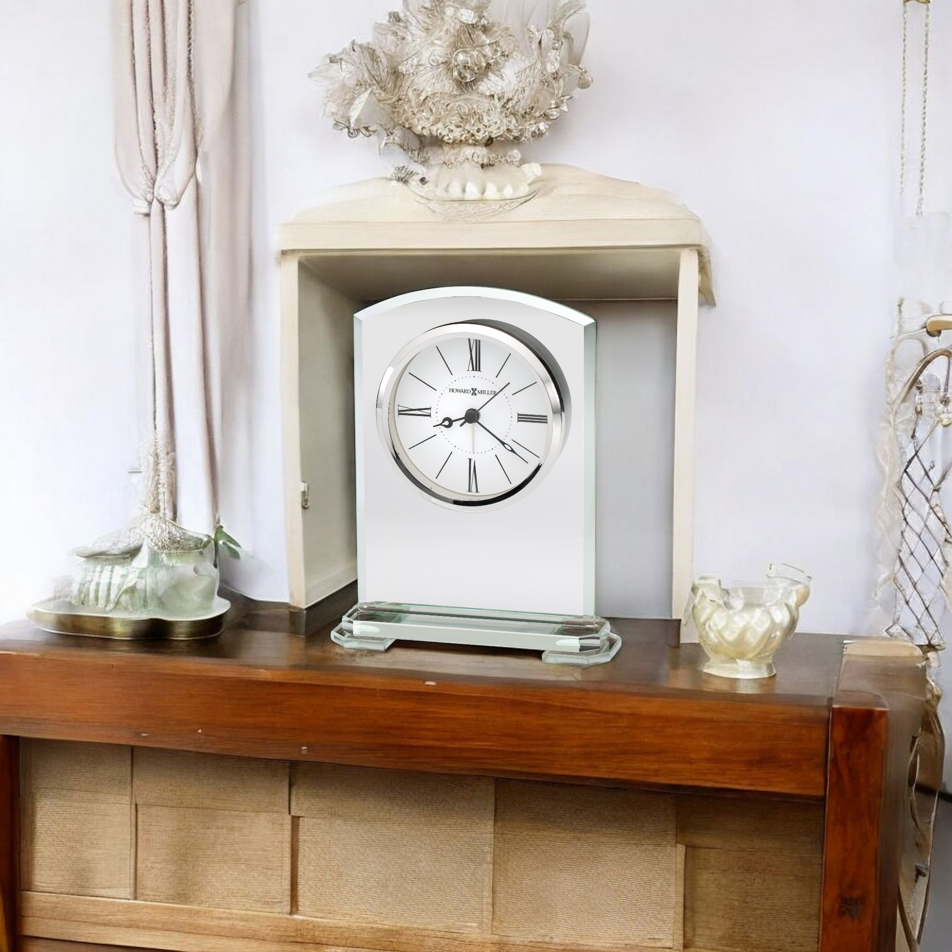 A decorative clock displayed on a wooden shelf against a light-colored backdrop.
