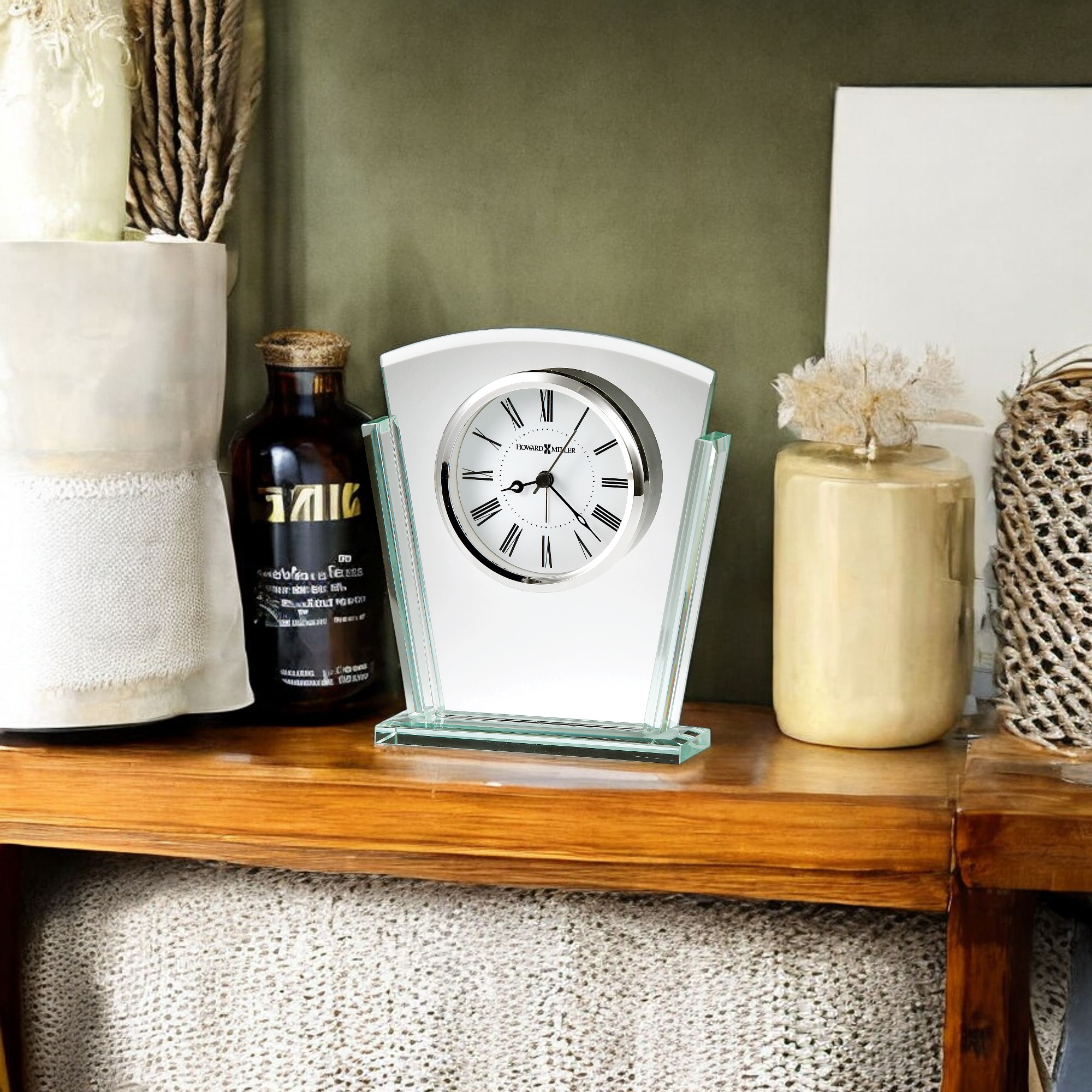 A stylish tabletop clock on a wooden shelf, surrounded by various decorative items.