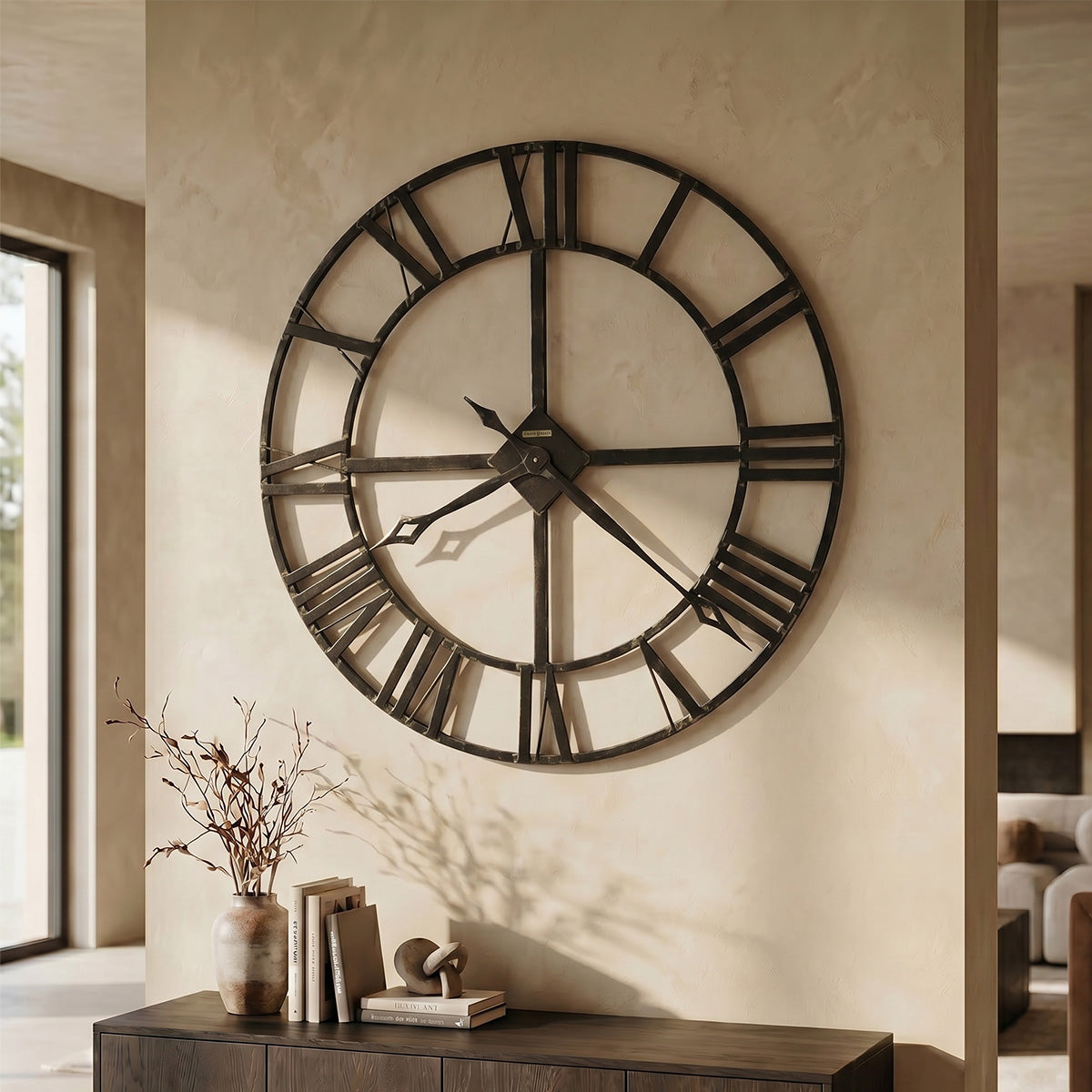 Large wall clock with Roman numerals on a beige wall in a home setting.