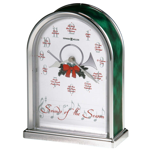 A decorative clock with musical notes and a holiday theme, featuring a green arch and a red bow.
