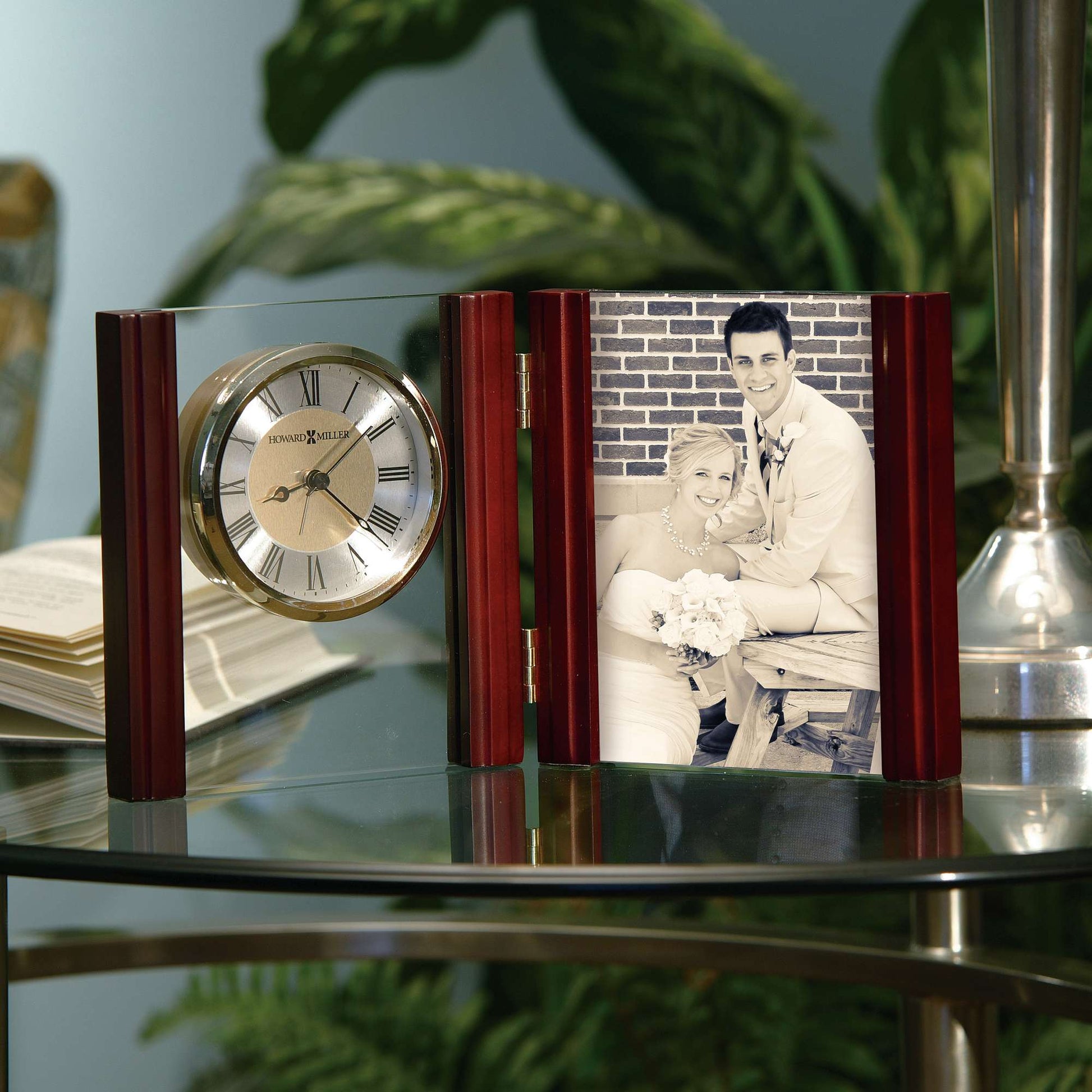 A decorative clock and photo frame displayed on a glass table.