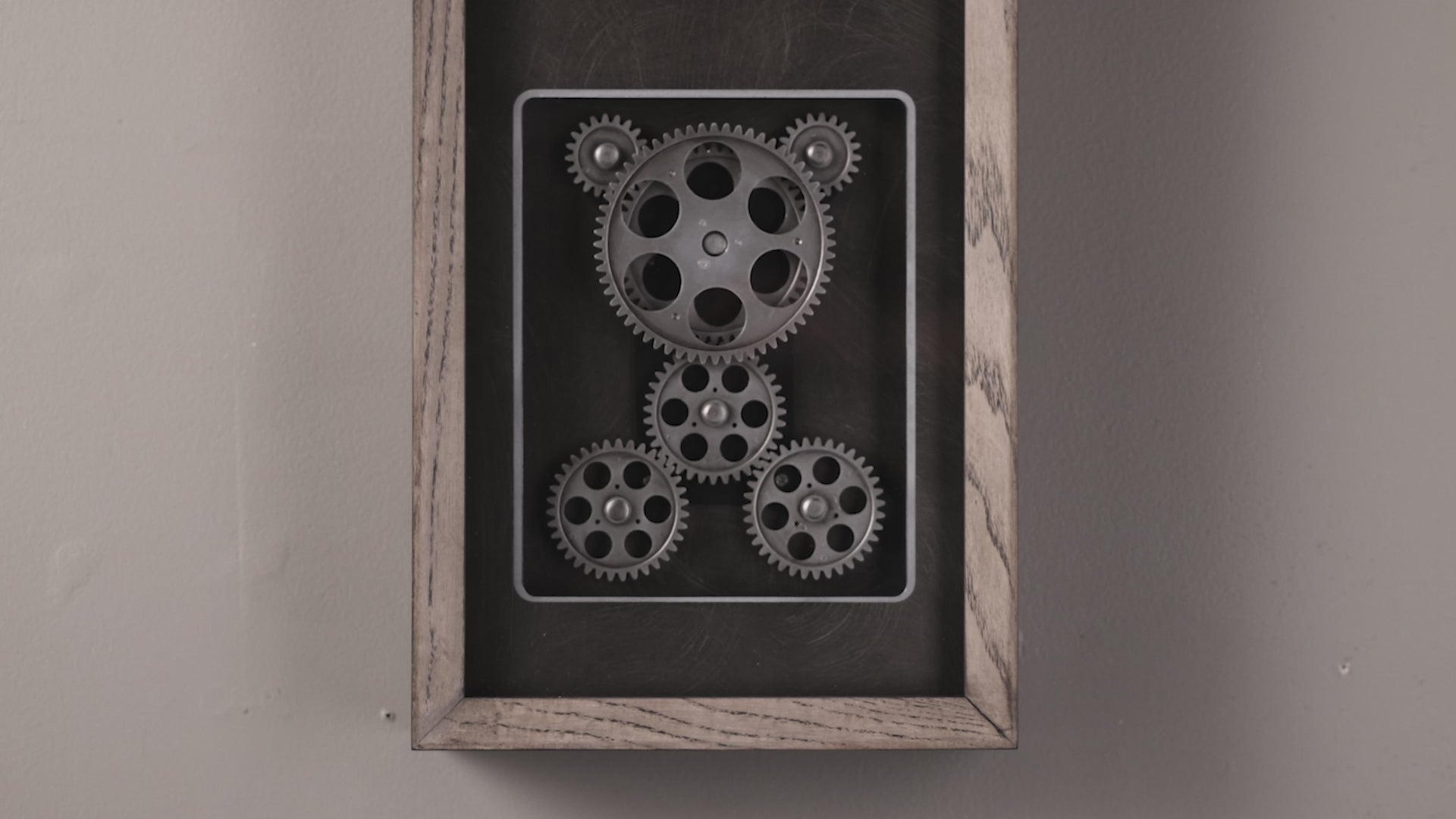 A framed artwork featuring a bear shape created from metal gears.