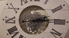 A vintage clock with Roman numerals and visible gears in the center.