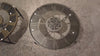 Top view of two intricate circular clock mechanisms on a textured surface.