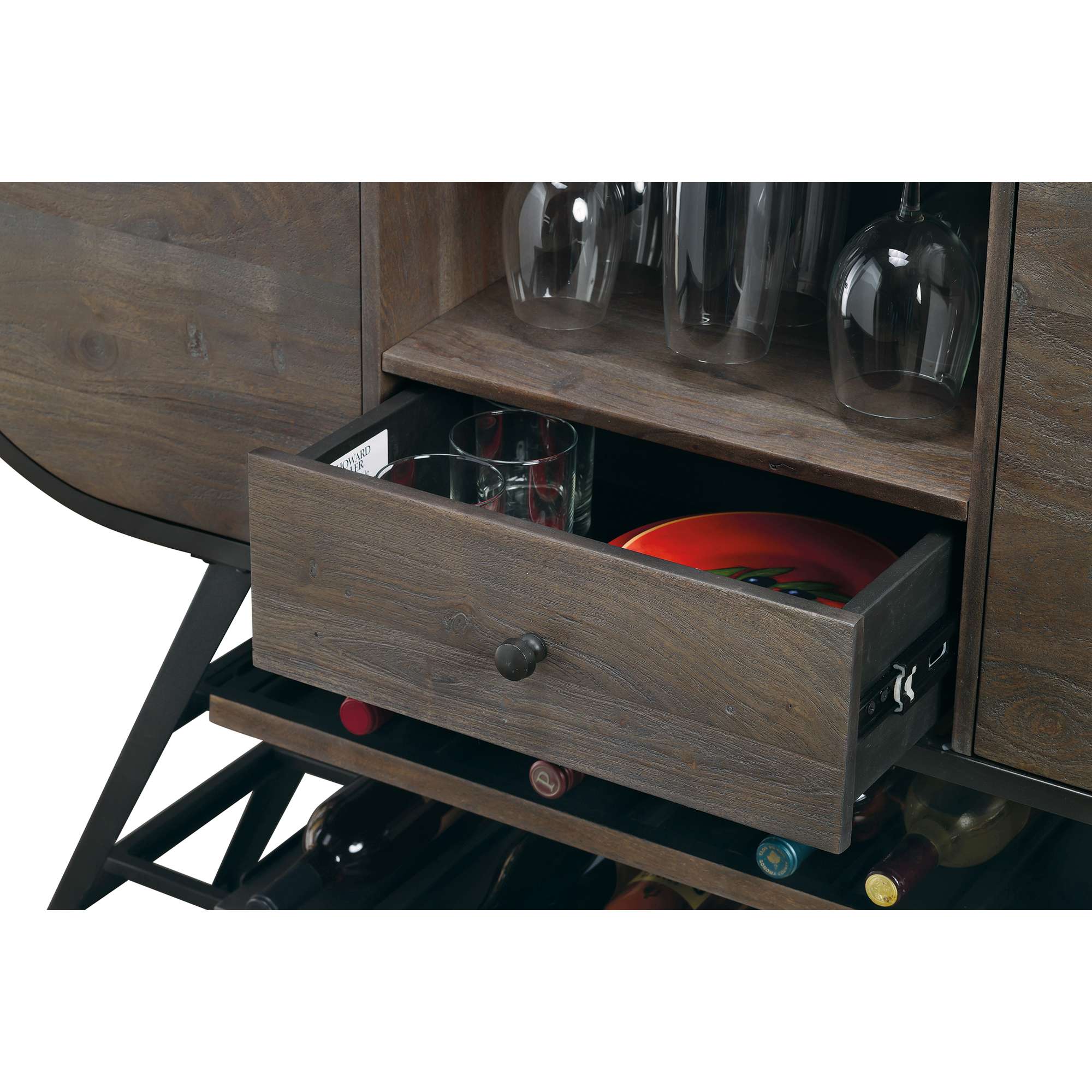 Open drawer in a wooden cabinet displaying glasses and a red plate.